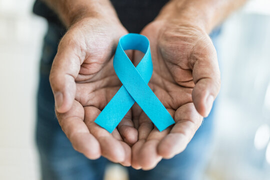 Senior man holding a blue cancer awareness ribbon