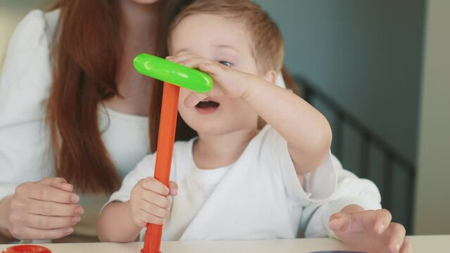 the child collects a toy pyramid. mom plays with son at home happy family. development of fine motor skills in a newborn child fun. happy family mom and baby play pyramid game. preschool education