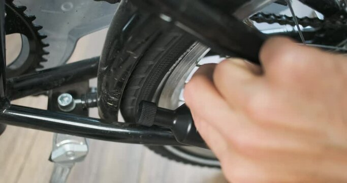 Man hand turns on the bicycle dynamo. Brings the dynamo closer to the tire. Close-up, bike, indoors.