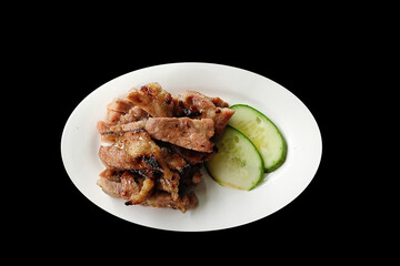 Grilled pork neck on a white plate, isolated on a black background with clipping path, is a popular appetizer in Thailand.