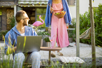Happy young family with laptop and healthy lunch at backyard