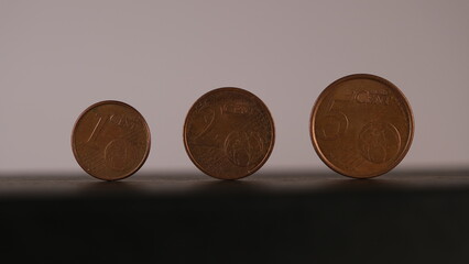 Coins of 1, 2 and 5 European cents placed in a row, money saved on black and white background. 
