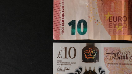 Obraz premium 10 pound bill next to 10 euro bill with black background. Concept Banknote comparison. Concept Change from British to European money.