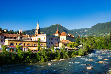 Fototapeta na wymiar Der Fluss Passer durch Meran in Südtirol, mit Stadt und Bergpanorama im Weitwinkel