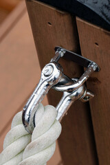 Shining stainless straght shackle with mooring rope tide up on the wood deck. Close up macro...