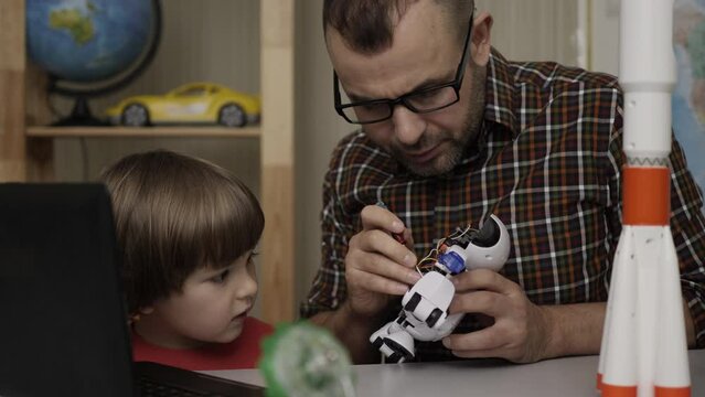 Dad with Little Son Assemble Robot at Home. Education Science, Technology Children, Programming Electronic Robotics School Lesson. Child Boy And Teacher, Assembling Robots in Modern Classroom.