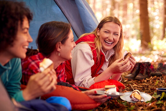 Group Of Female Friends On Camping Holiday In Forest Lying In Tent Eating S'mores