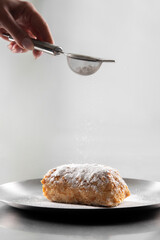 Napoleon cake with icing sugar on black background . Decorating napoleon cake with powdered sugar.