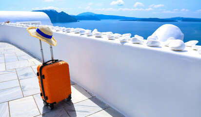 The banner of travel  in summer concept with Orange luggage with hat and landscape view of Oia town...