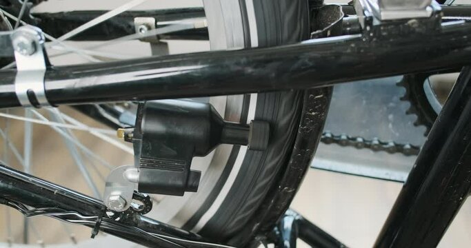 Bicycle dynamo, wheel and pedal rotation, close-up. A vintage bicycle dynamo that spins electricity around a tire.