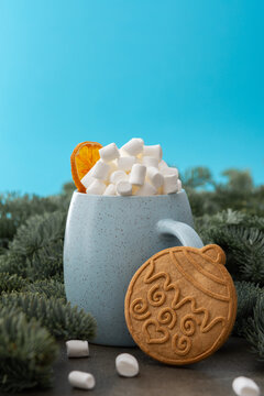 Christmas drink with marshmallows in a mug with gingerbread cookies among fir branches