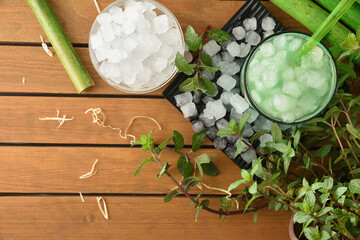 Fototapeta na wymiar Natural iced mint beverage on wooden table with plant top