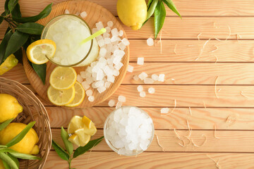 Lemonade with ice on wooden table with cut fruit top