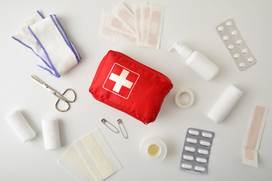 Assortment of emergency first aid kit objects on white table.