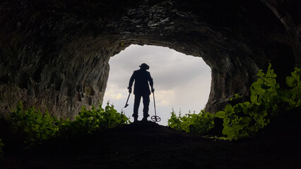 treasure hunter with metal detector searching inside the cave in the historical texture - obrazy, fototapety, plakaty