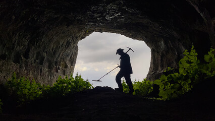 Obraz premium treasure hunter with metal detector searching inside the cave in the historical texture