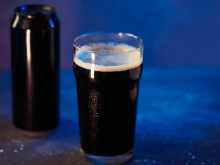 A pint of craft beer stout on a blue background. A glass of dark beer