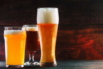 Three pints of a glass of craft or draft beer in the bar on a wooden table. Different beers on the...