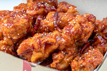 Spicy Korean fried chicken with spicy sauce traditional Korean food, Spicy sauce Fried chicken with chili on paper bucket.