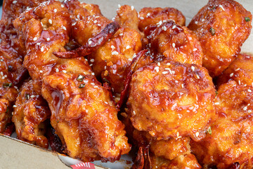 Spicy Korean fried chicken with spicy sauce traditional Korean food, Spicy sauce Fried chicken with chili on paper bucket.