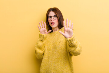 young adult pretty woman feeling terrified, backing off and screaming in horror and panic, reacting...