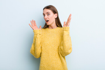 young adult pretty woman looking shocked and astonished, with jaw dropped in surprise when...