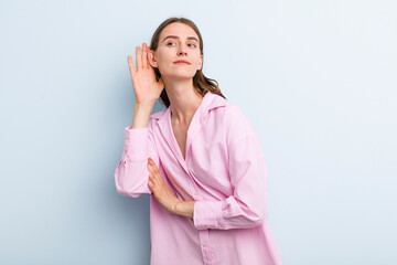 young adult pretty woman looking serious and curious, listening, trying to hear a secret...