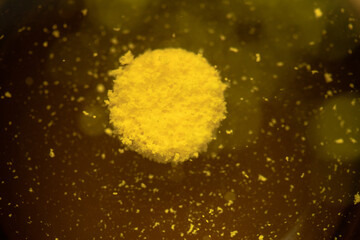 A yellow effervescent tablet dissolves in a glass of water on a black background, a nutritional supplement of vitamins.Close-up,top view - obrazy, fototapety, plakaty