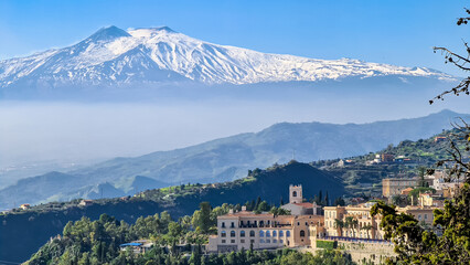 Luxury San Domenico Palace Hotel with panoramic view on snow capped Mount Etna volcano on sunny day...