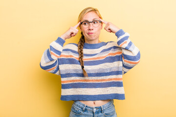 young adult  blonde woman looking concentrated and thinking hard on an idea, imagining a solution...
