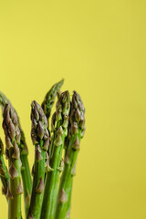 Bunch of fresh green asparagus on a yellow background. Healthy eating concept.