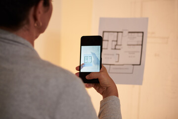 Close-up image of architect taking photo of house floor plan to send to colleague