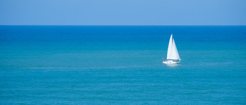 Single sailboat on the calm blue waters of the Mediterranean Sea of the coast of Italy.