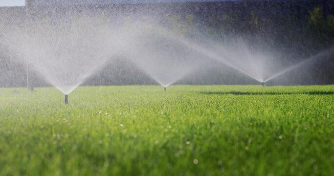 Irrigation system waters the green lawn - water is supplied from nozzles under pressure