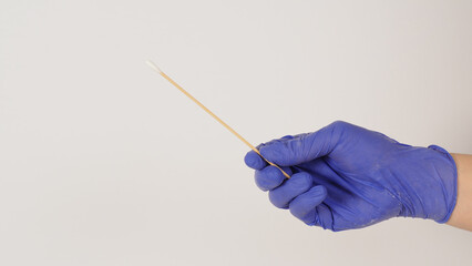 Cotton stick for swab test in hand with violet medical gloves or latex glove on white background.