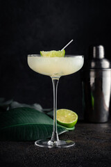 Daiquiri cocktail in a beautiful glass with a slice of lime, crushed ice and a straw. Tropical alcoholic drink with rum