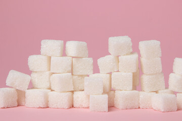 Sugar cubes on a pink background. Excessive consumption of sugar