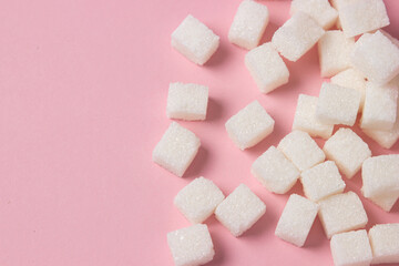 Sugar cubes on a pink background. Excessive consumption of sugar