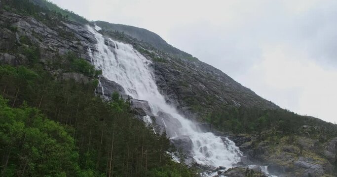 Wonderful landscapes in Norway. Vestland. Beautiful scenery of Langfossen waterfall on the Akrafjorden fjord. Mountains and trees on rocks in background. Sunny day 4K UHD 59,94fps ProRes 422 HQ 10 bit
