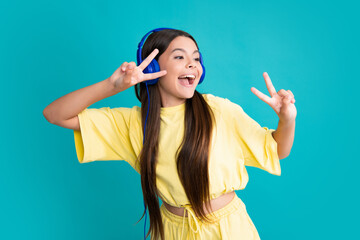 Teen girl in headphones listen to music. Wireless headset device accessory. Child enjoys the music in earphones on yellow background. Excited face, cheerful emotions of teenager girl.