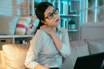 asian female employee getting stiff shoulders due to lowering head to use computer for long hours. taiwanese woman is kneading her sore body with uncomfortable look.