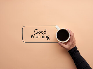 A hand is holding a cup of coffee with the word good morning. Breakfast and morning coffee
