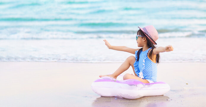 Banner of adorable asian little girl wear sunglass and hat is happy to play sea water on the beach for the family vacation trip in summer holiday.