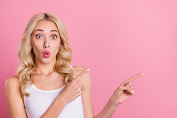 Portrait of attractive stunned blond girl demonstrating copy blank space ad look idea isolated over pink pastel color background
