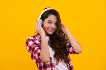 Teenager in modern wireless headphones enjoying song music in audio app, listening to her favorite music over yellow studio background. Happy teenager girl casual wear.