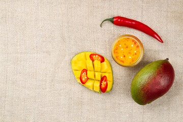 Top view of Whole mango, whole chili pepper, sliced hot pepper, cutted half of mango and Spicy...