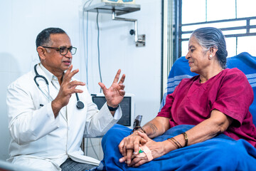 Doctor near patient bed advising to elderly woman at hospital - concept of diagnosis, confidence...