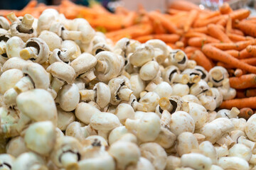 Close-up of fresh champignons on the counter in the store, fresh carrots in the background