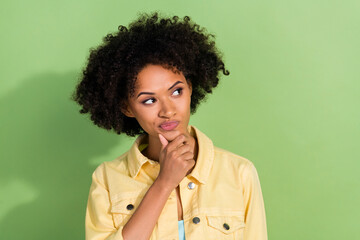 Photo of uncertain suspicious woman dressed yellow jeans jacket arm chin empty space isolated green...