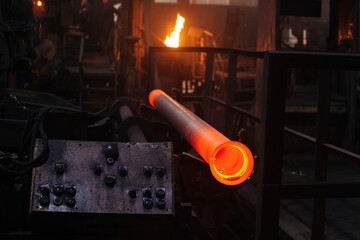 Freshly cast red hot iron pipe at the foundry